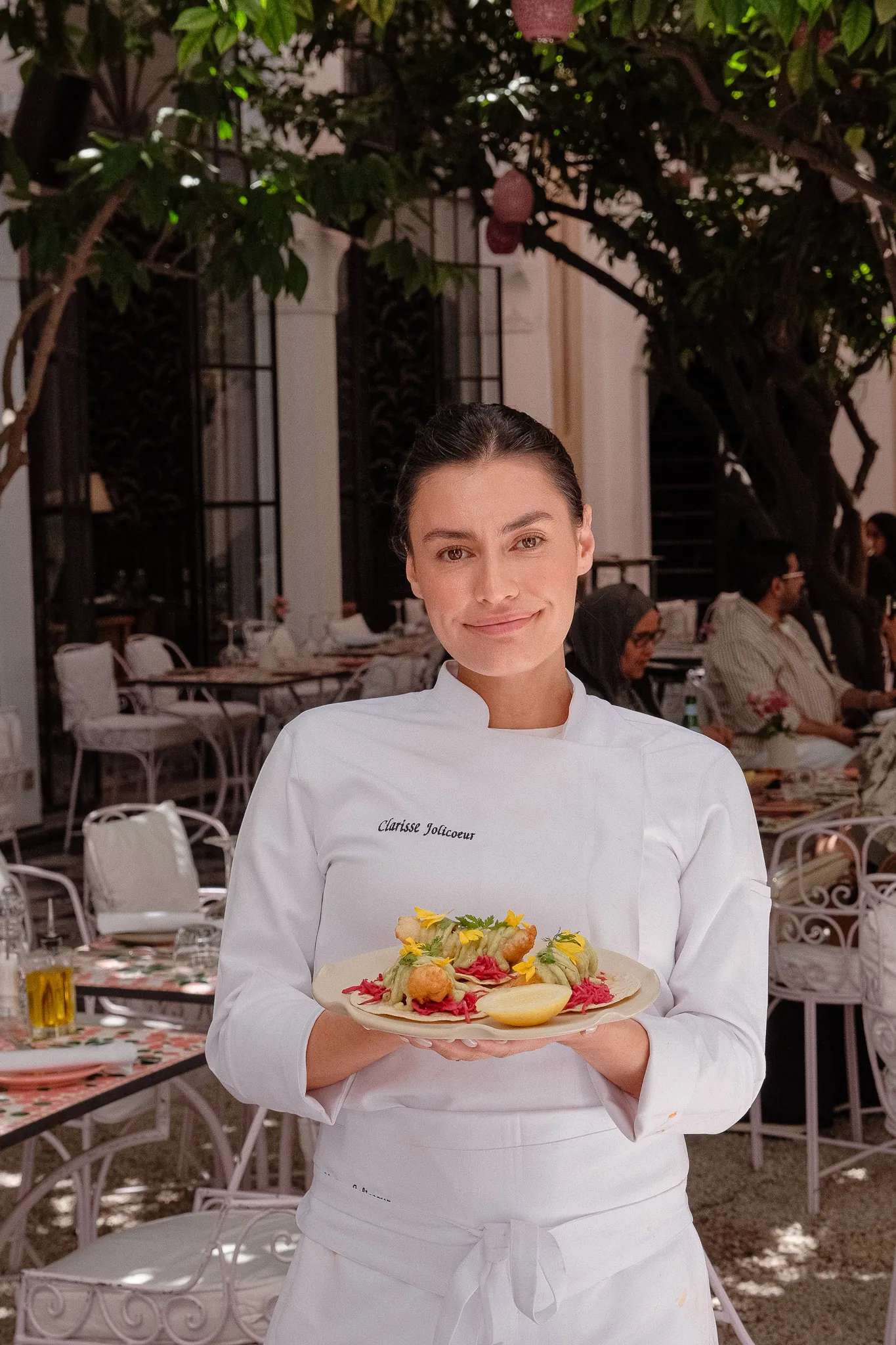 La cheffe Clarisse Jolicoeur, un plat à la main, dans le patio